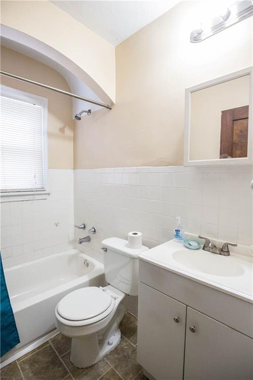 full bathroom featuring wainscoting, toilet, shower / bath combo with shower curtain, vanity, and tile walls