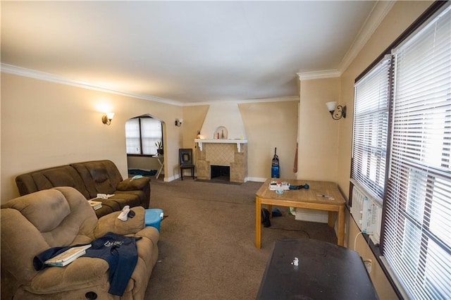 carpeted living area featuring a large fireplace, baseboards, arched walkways, and crown molding