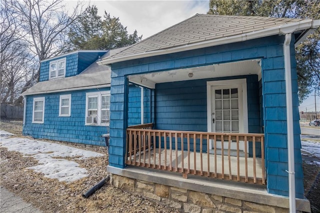 exterior space with a porch and roof with shingles