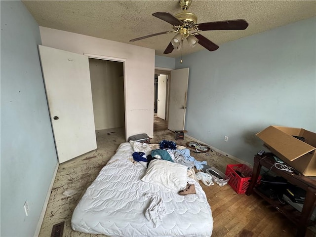 bedroom with hardwood / wood-style flooring, ceiling fan, and a textured ceiling