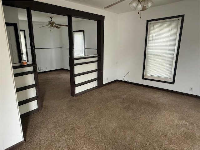 unfurnished room with dark carpet and ceiling fan