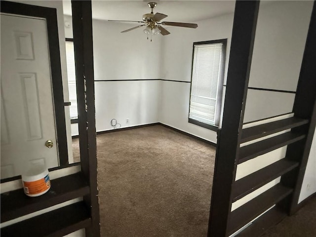 empty room with dark colored carpet and ceiling fan