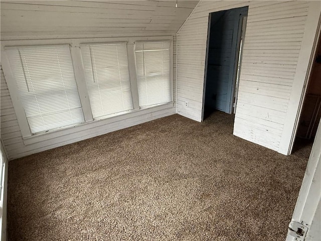 unfurnished bedroom with lofted ceiling and dark carpet