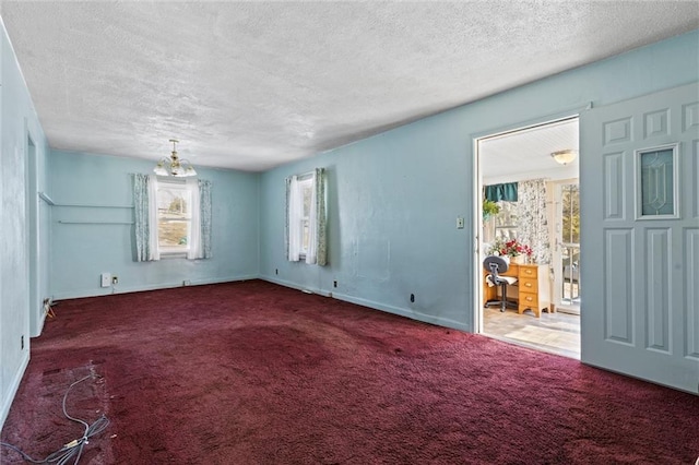 unfurnished room with a chandelier, a textured ceiling, and dark carpet