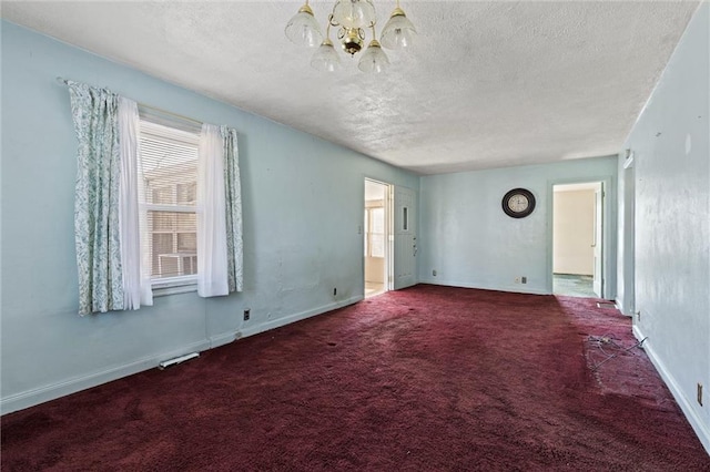 carpeted spare room featuring a notable chandelier and a textured ceiling