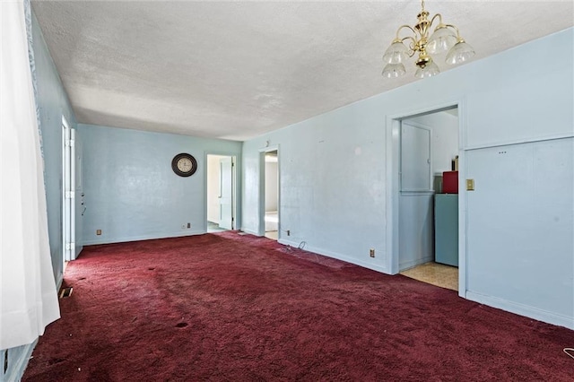 unfurnished room with an inviting chandelier, a textured ceiling, and carpet