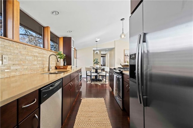 kitchen with sink, hanging light fixtures, stainless steel appliances, dark hardwood / wood-style floors, and decorative backsplash