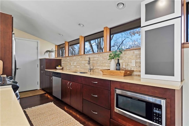 kitchen with vaulted ceiling, appliances with stainless steel finishes, sink, backsplash, and dark hardwood / wood-style flooring