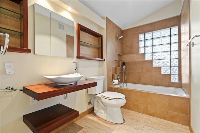 full bathroom with toilet, sink, tiled shower / bath, vaulted ceiling, and tile patterned flooring