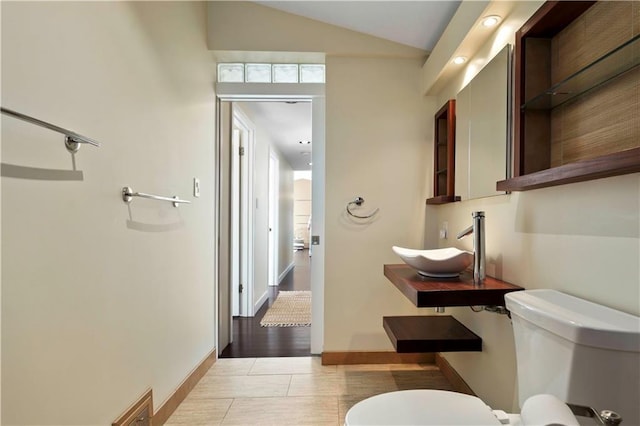 bathroom featuring lofted ceiling, sink, tile patterned floors, and toilet