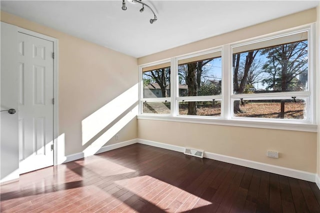 unfurnished room featuring hardwood / wood-style flooring and track lighting