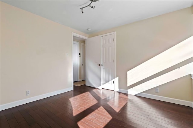 empty room featuring dark wood-type flooring and track lighting