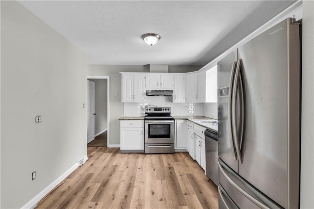 kitchen with backsplash, light hardwood / wood-style floors, white cabinets, and appliances with stainless steel finishes