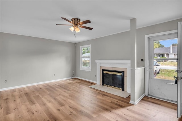 unfurnished living room with crown molding, light hardwood / wood-style flooring, a tile fireplace, and ceiling fan