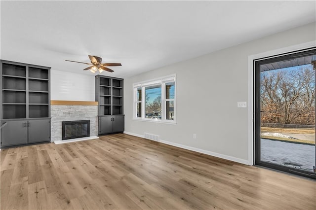 unfurnished living room with ceiling fan, a fireplace, light hardwood / wood-style floors, and built in features