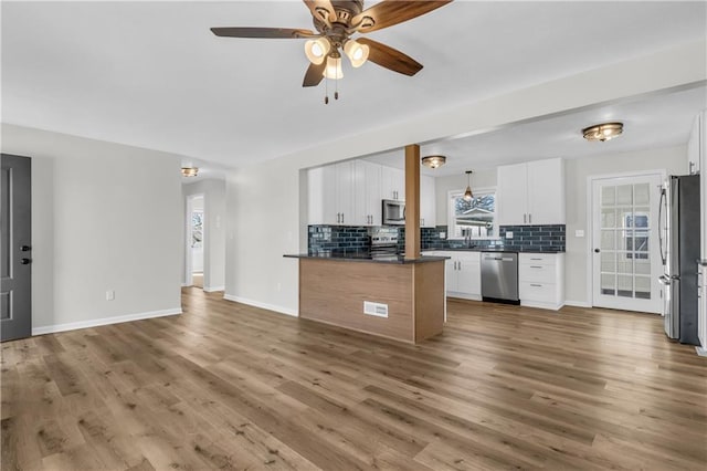 kitchen with white cabinetry, stainless steel appliances, wood-type flooring, and decorative backsplash