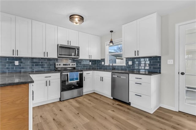 kitchen with pendant lighting, appliances with stainless steel finishes, sink, and white cabinets