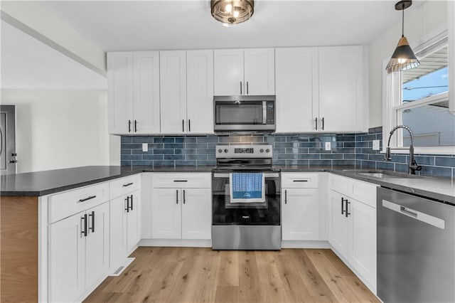 kitchen featuring appliances with stainless steel finishes, decorative light fixtures, sink, white cabinets, and kitchen peninsula