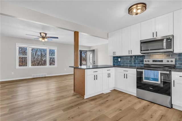 kitchen with stainless steel appliances, light hardwood / wood-style floors, white cabinets, decorative backsplash, and kitchen peninsula