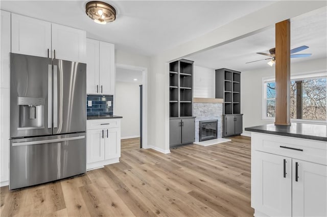 kitchen with a fireplace, backsplash, stainless steel fridge, and white cabinets