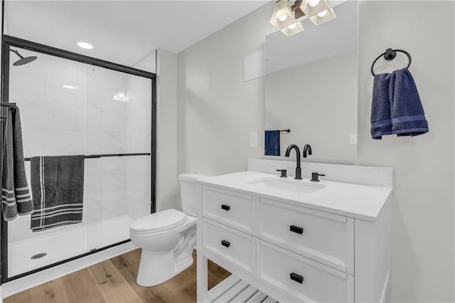 bathroom featuring a shower with door, wood-type flooring, vanity, and toilet