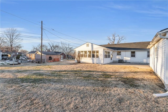 rear view of property with a yard and central air condition unit