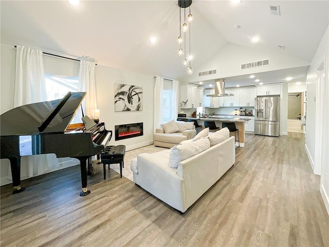 living room with high vaulted ceiling and light hardwood / wood-style floors