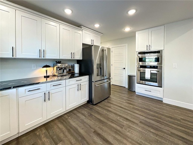 kitchen featuring stainless steel appliances, white cabinets, dark hardwood / wood-style flooring, and dark stone counters