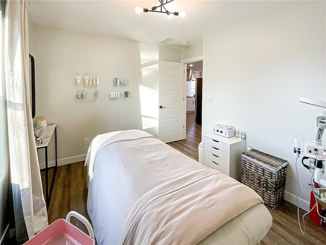 bedroom with dark hardwood / wood-style floors and a notable chandelier