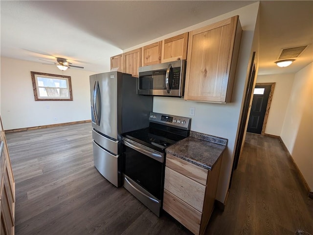 kitchen featuring ceiling fan, appliances with stainless steel finishes, dark hardwood / wood-style flooring, dark stone counters, and light brown cabinets