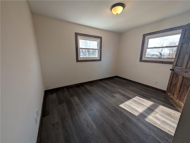 spare room with dark wood-type flooring and a healthy amount of sunlight