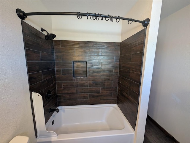 bathroom with toilet and tiled shower / bath