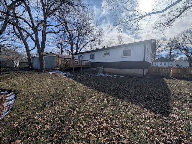 rear view of house featuring a storage shed, a yard, central AC, and a wooden deck