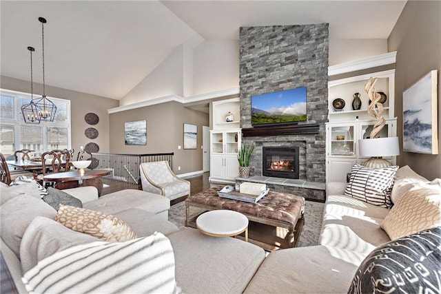 living room featuring hardwood / wood-style flooring, built in features, high vaulted ceiling, a notable chandelier, and a stone fireplace