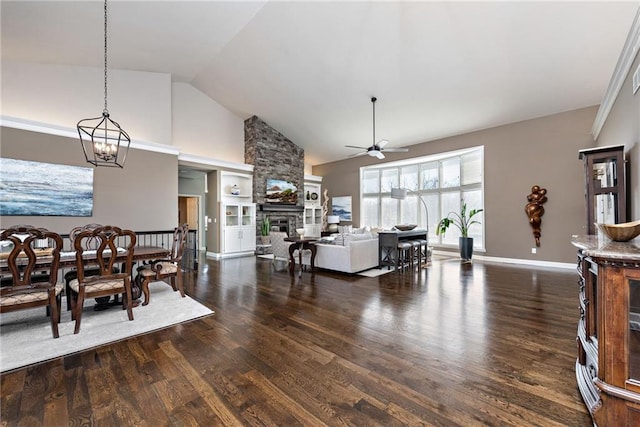 dining area featuring a stone fireplace, ceiling fan with notable chandelier, high vaulted ceiling, and dark hardwood / wood-style floors