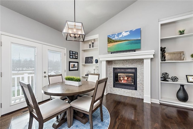 dining space with a tile fireplace, dark hardwood / wood-style floors, french doors, lofted ceiling, and built in shelves