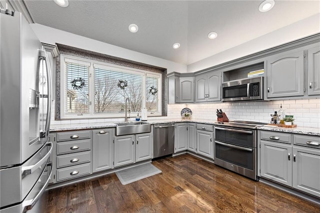 kitchen featuring sink, gray cabinetry, vaulted ceiling, dark hardwood / wood-style flooring, and stainless steel appliances