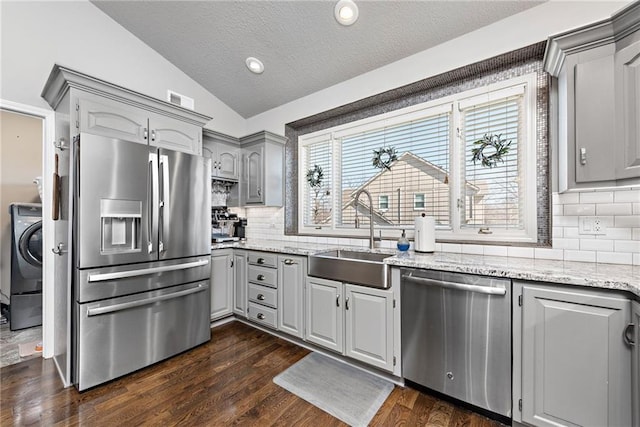 kitchen featuring dark wood-type flooring, lofted ceiling, sink, gray cabinets, and stainless steel appliances