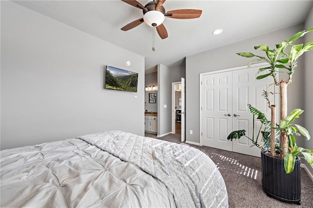 bedroom with connected bathroom, dark carpet, a closet, and ceiling fan