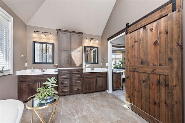 bathroom with lofted ceiling, vanity, and a bath