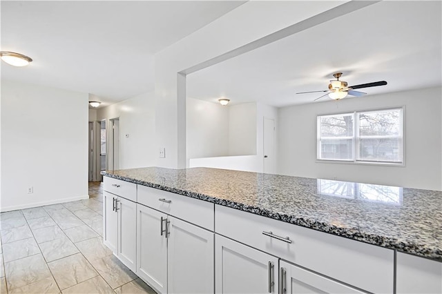 kitchen featuring light stone counters, white cabinetry, and ceiling fan