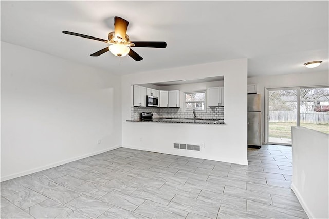 unfurnished living room with sink and ceiling fan