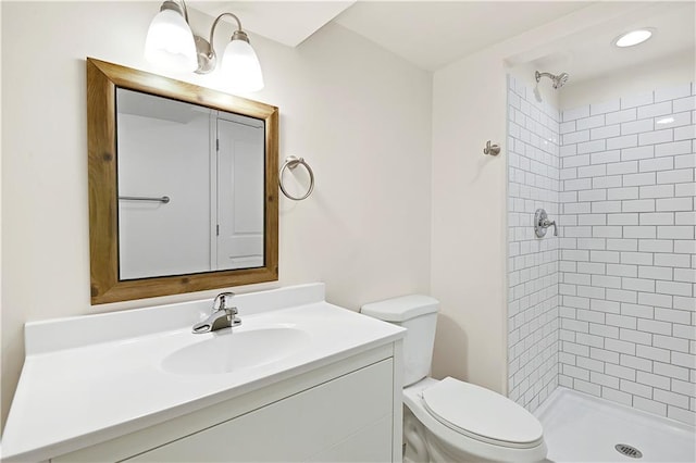 bathroom featuring vanity, toilet, and a tile shower