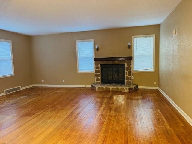 unfurnished living room with a stone fireplace and hardwood / wood-style flooring