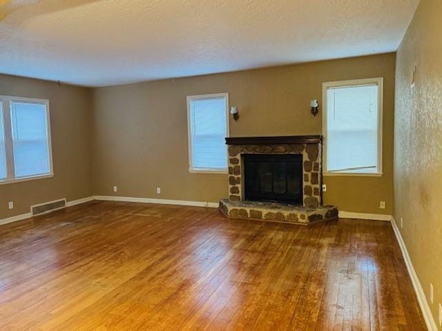 unfurnished living room with a fireplace, hardwood / wood-style floors, and a textured ceiling