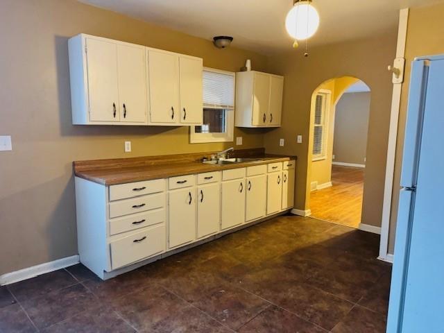 kitchen with white cabinetry, white fridge, and sink