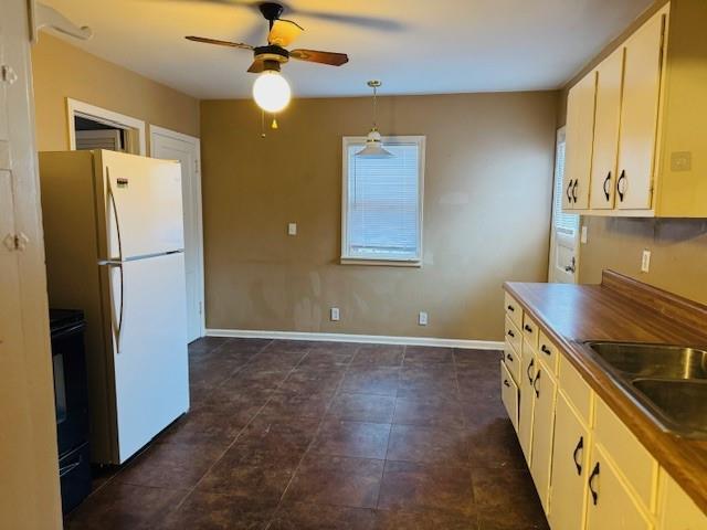 kitchen with sink, ceiling fan, range with electric stovetop, decorative light fixtures, and white fridge