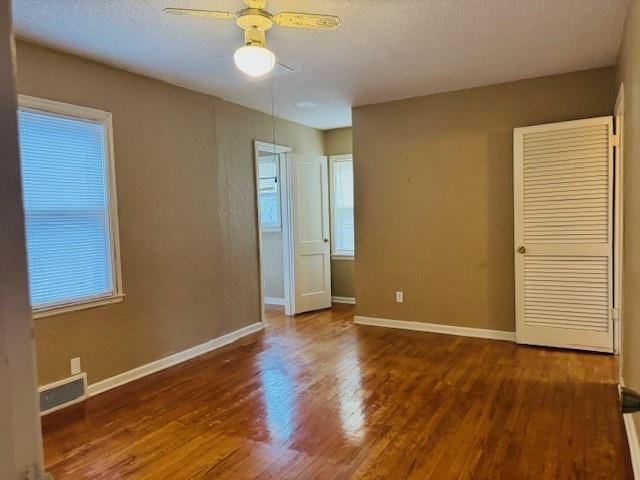 unfurnished bedroom featuring ceiling fan, dark hardwood / wood-style floors, and a textured ceiling