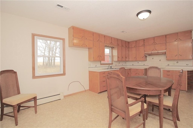 kitchen featuring tasteful backsplash, visible vents, baseboards, light countertops, and under cabinet range hood