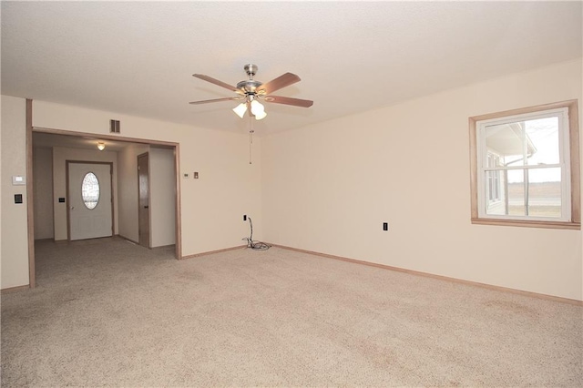 spare room with baseboards, visible vents, ceiling fan, and light colored carpet